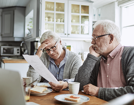 Man and woman eating breakfast, reviewing paperwork and looking concerned